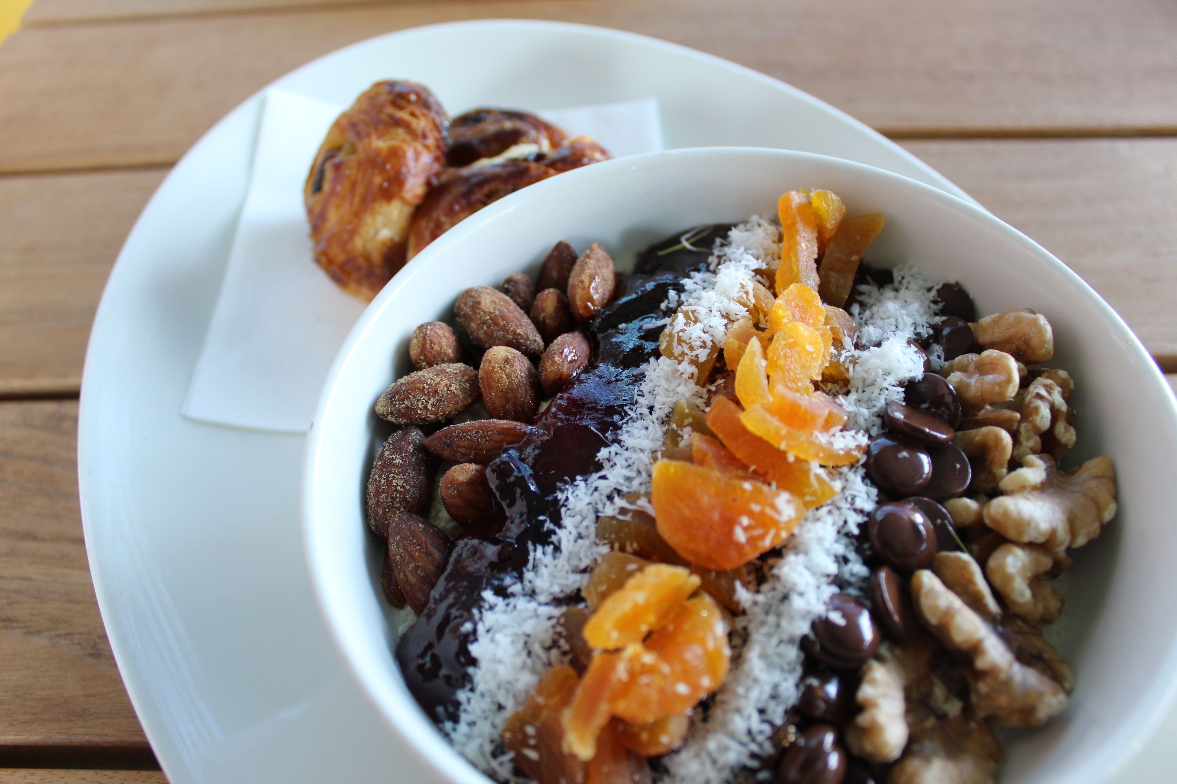 A bowl of mixed nuts and dried fruits on a white plate.