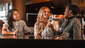 Trois personnes sont assises au bar, devant des coupes à champagne, dont l’une est décorée d’une fraise.