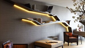 Un intérieur moderne agrémenté d’une bibliothèque intégrée, d’un coin salon avec un banc rembourré et d’un arbre décoratif.