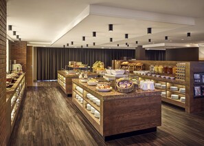 Een buffetopstelling met diverse etenswaren en bestek, een bakstenen muur en een houten vloer.