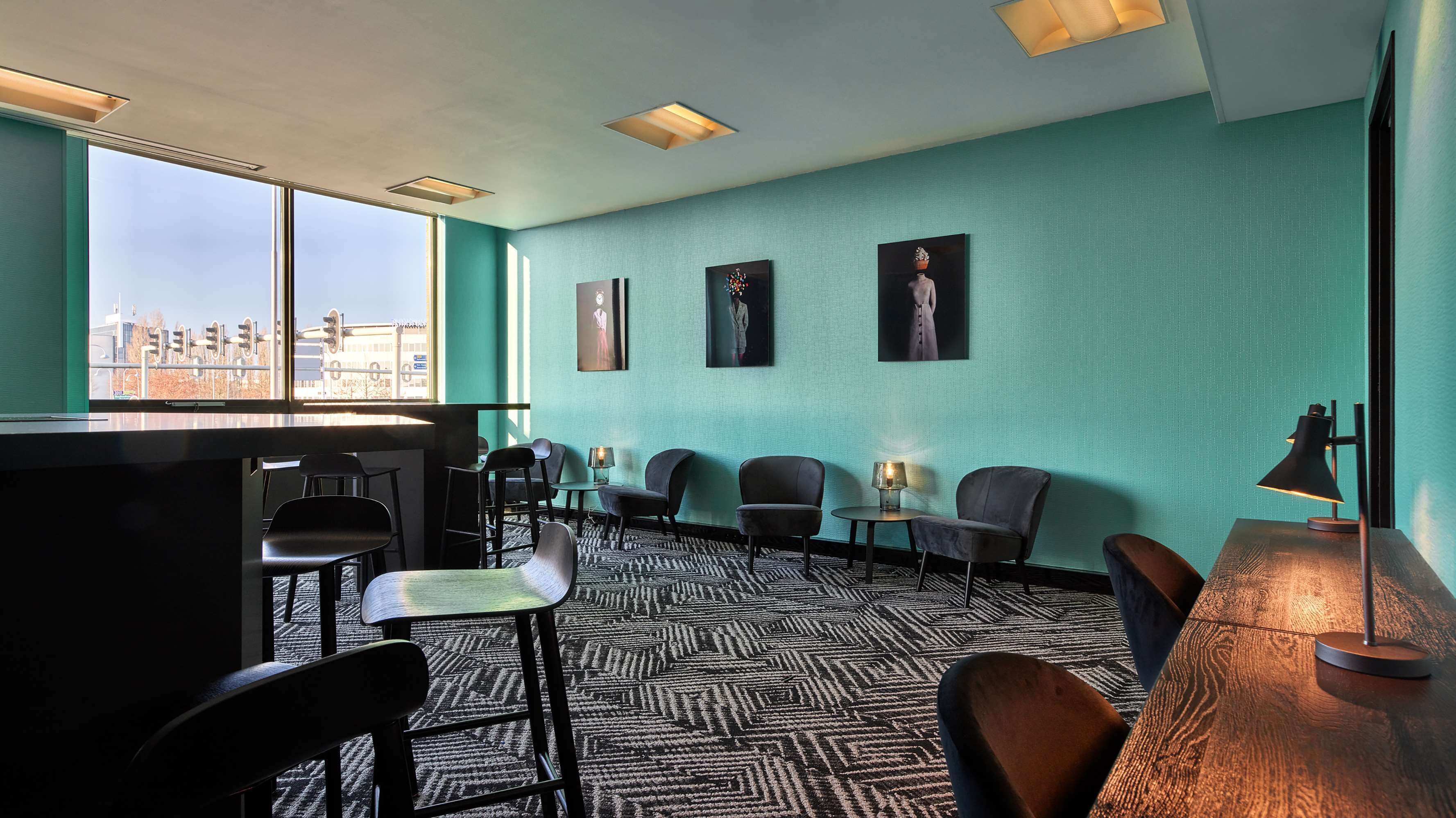 A modern room with a large window, a bar area, and several chairs.