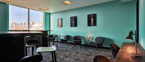 A modern room with a large window, a bar area, and several chairs.