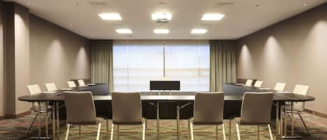 A conference room with a large table, six chairs, and a projector screen.