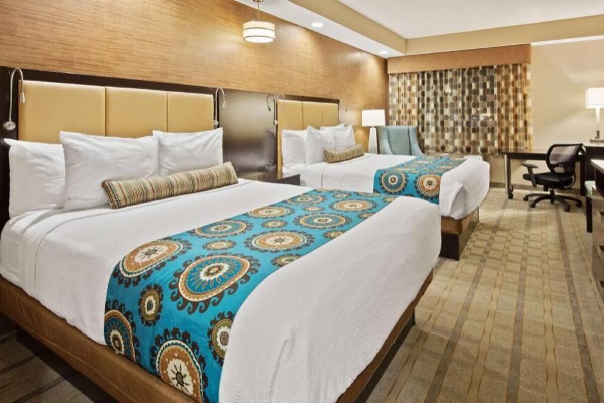 Une chambre d’hôtel avec deux lits, un bureau, une chaise, une télévision et une salle de bain.