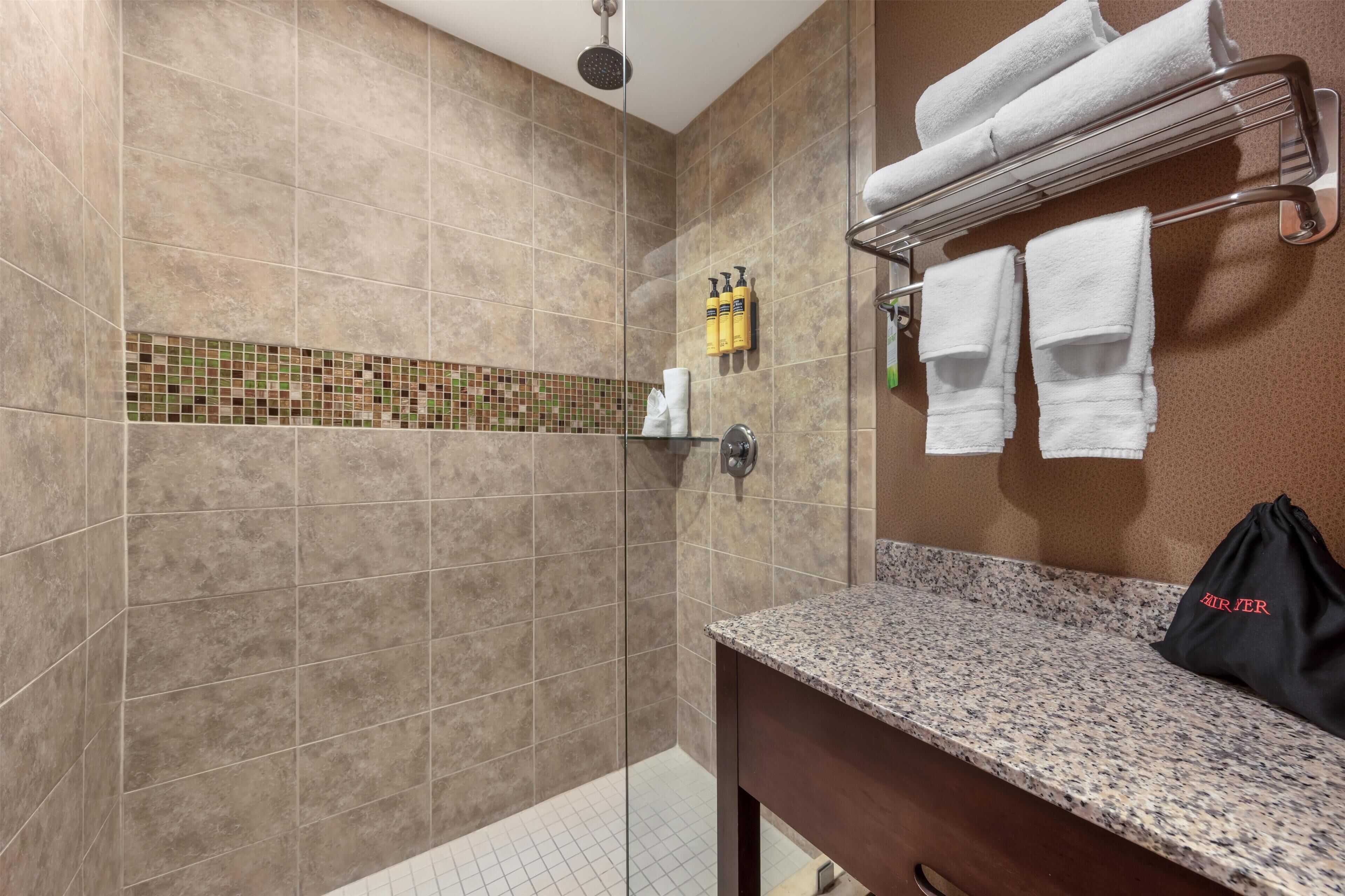 Une salle de bain avec une douche, un porte-serviettes et un lavabo.