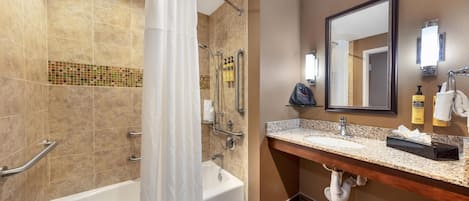 Un baño con bañera, ducha y tocador con espejo.
