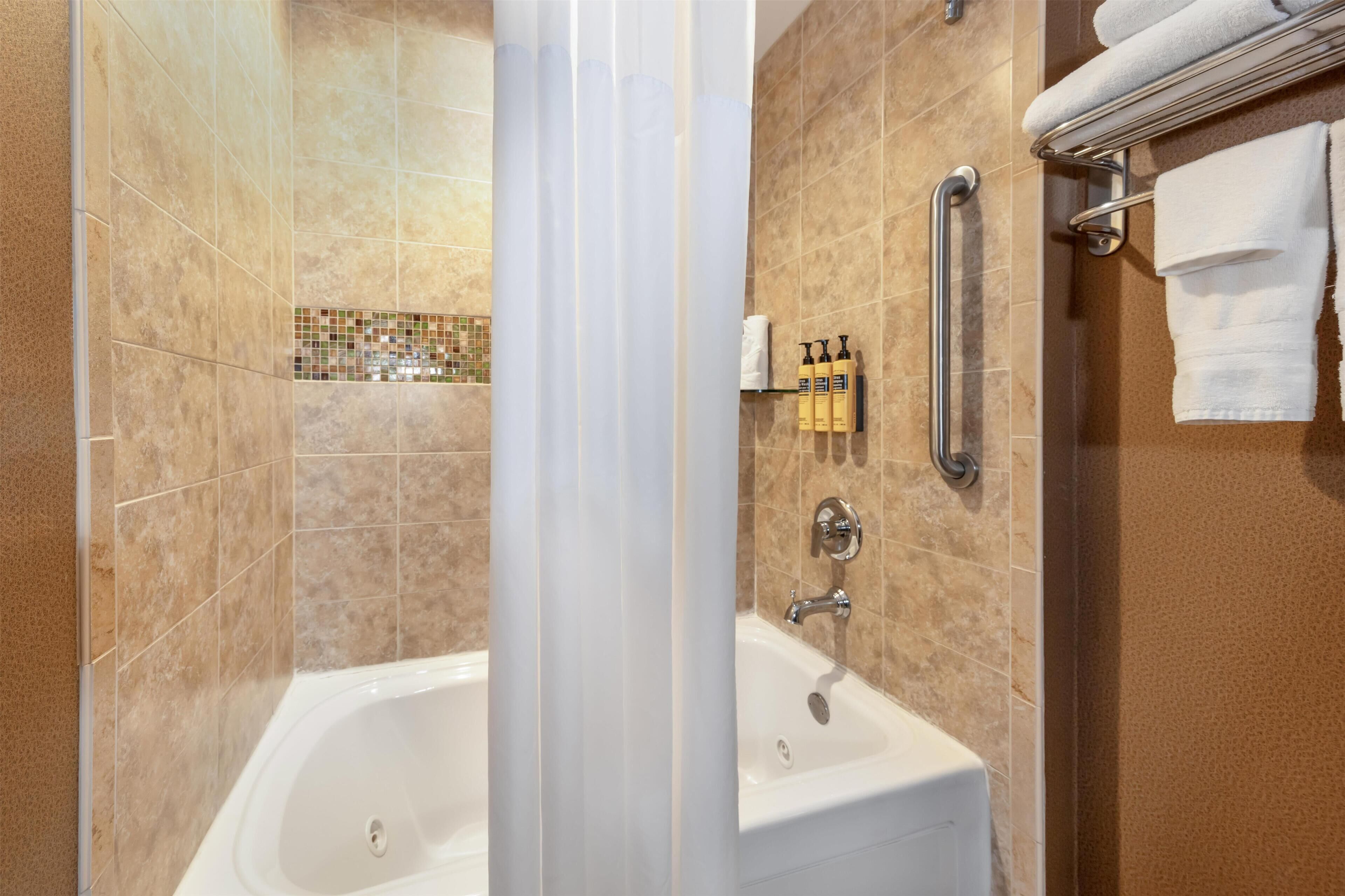 A bathroom with a bathtub, a shower area, and a towel rack.