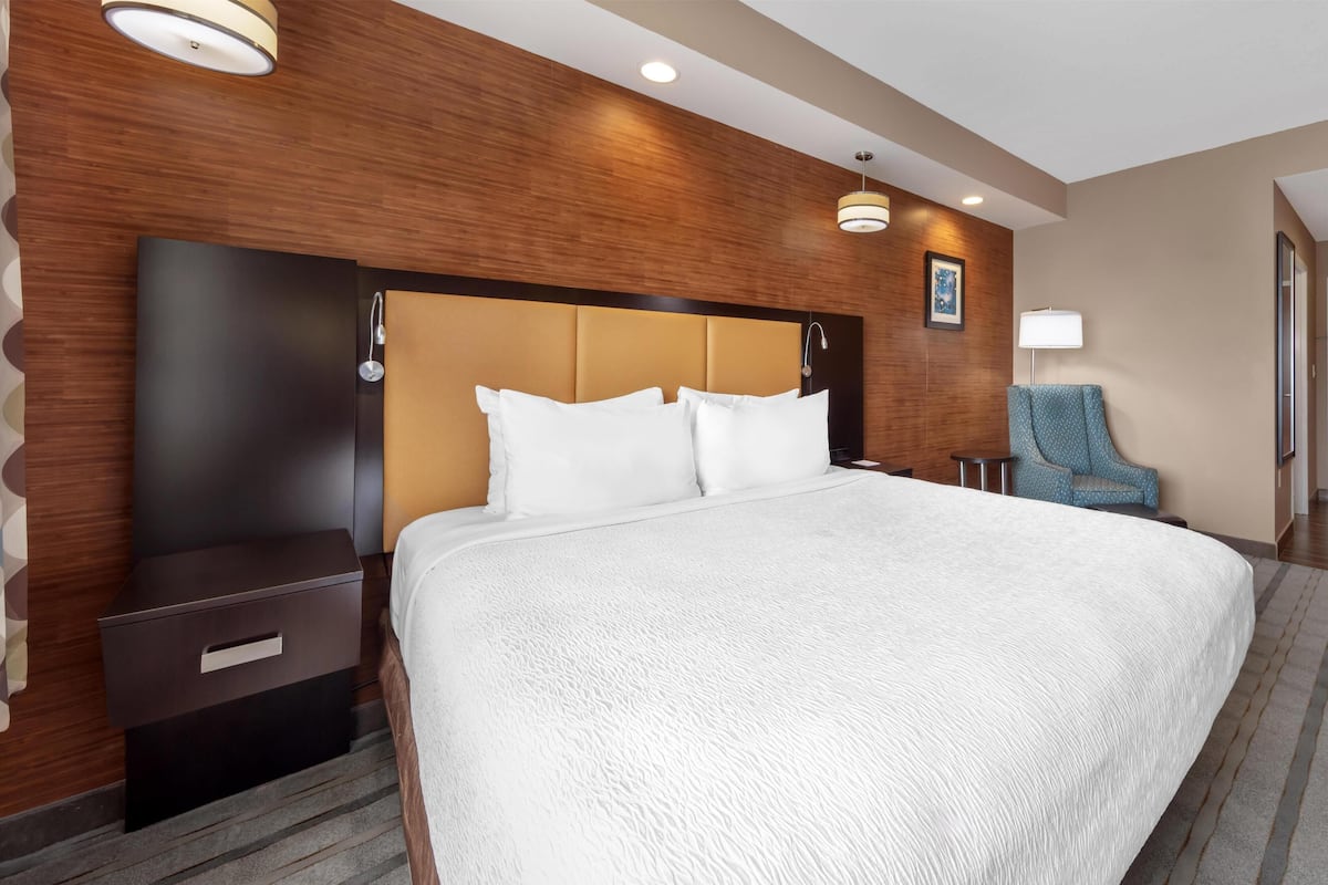Ein Hotelzimmer mit einem großen Bett, einem Nachttisch, einer Lampe und einem Sessel.