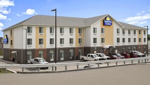 A Days Inn & Suites building with a parking lot and a clear sky. - Days Inn & Suites by Wyndham Belmont (Belmont)