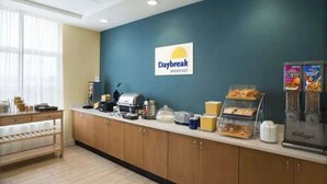 A breakfast counter with a sign for 'Daybreak Breakfast', a coffee machine, a kettle, and a variety of food items. - Days Inn & Suites by Wyndham Belmont (Belmont)