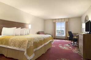 Een hotelkamer met een groot bed, een bureau, een stoel en een televisie.