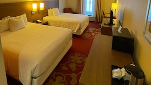 A hotel room with two beds, a desk, a chair, a lamp, and a window with curtains. - Days Inn & Suites by Wyndham Belmont (Belmont)