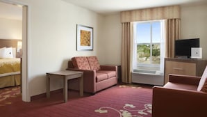 A hotel room with a bed, a sofa, a small table, a TV, and a window with a view. - Days Inn & Suites by Wyndham Belmont (Belmont)