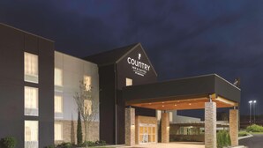 A Country Inn & Suites hotel with a modern design, featuring a covered entrance and a landscaped front yard.