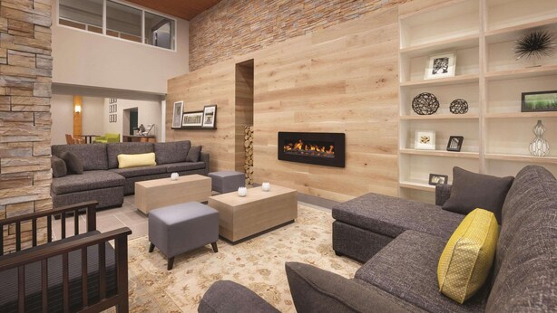 A modern living room with a fireplace, grey sofas, a coffee table, and a stone accent wall.