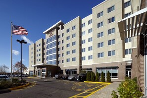 A multi-story hotel with a flat facade, large windows, and a parking lot with several cars. - Residence Inn Secaucus Meadowlands (Secaucus)
