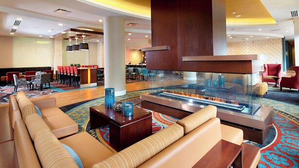 A hotel lobby with a large seating area, a reception desk, and a fire feature. - Residence Inn Secaucus Meadowlands (Secaucus)
