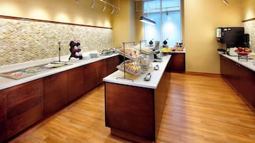 Una cocina de hotel moderna con mesas de buffet, armarios de madera y salpicadero de azulejos.