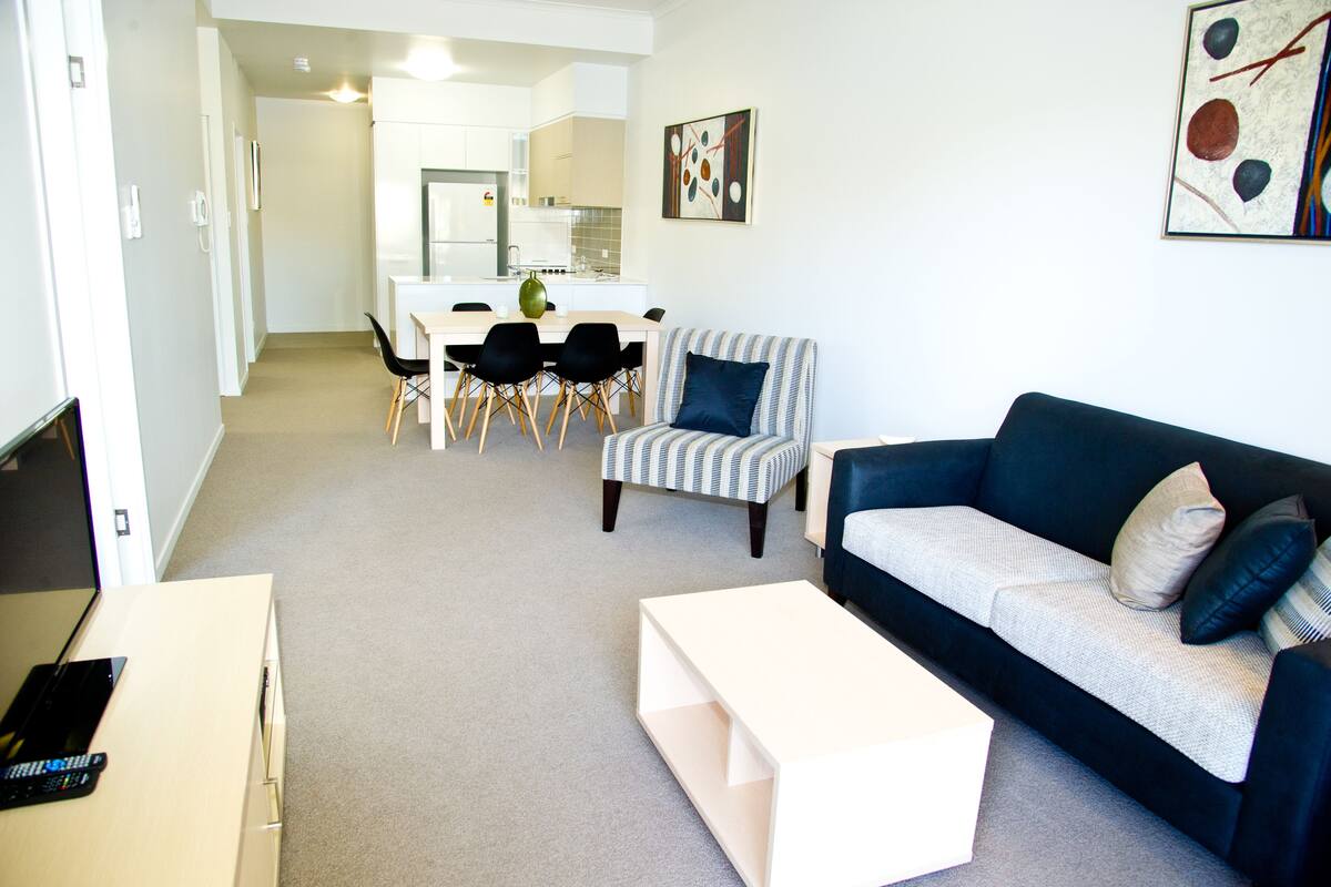 Ein modernes Wohnzimmer mit einer Couch, einem Couchtisch und einem Essbereich mit Stühlen und einem Tisch.