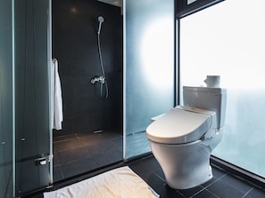 Un baño moderno con ducha envuelta en vidrio, inodoro y ventana grande.