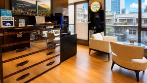 A modern hotel lobby with a large TV, a coffee shop named 'Relax Cafe,' and a view of the cityscape through large windows. - Hotel Relax (Taipei)