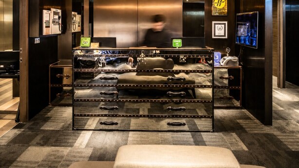 A hotel lobby with a luggage display, a reception desk, and a television screen. - Hotel Relax (Taipei)