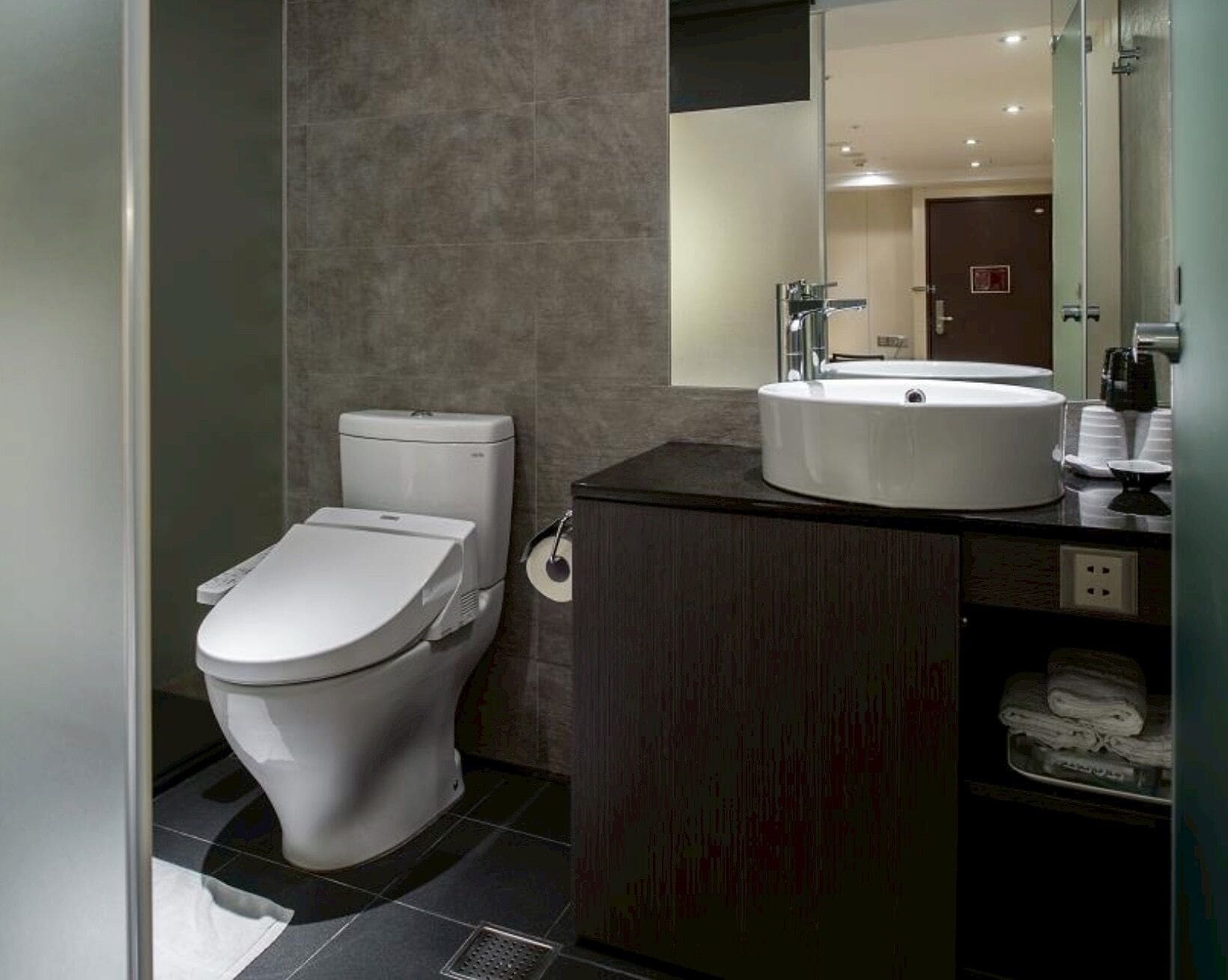 A modern bathroom with a toilet, sink, and mirror.