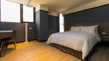 Een moderne hotelkamer met een houten vloer, een bed met wit beddengoed, een bureau en een stoel.