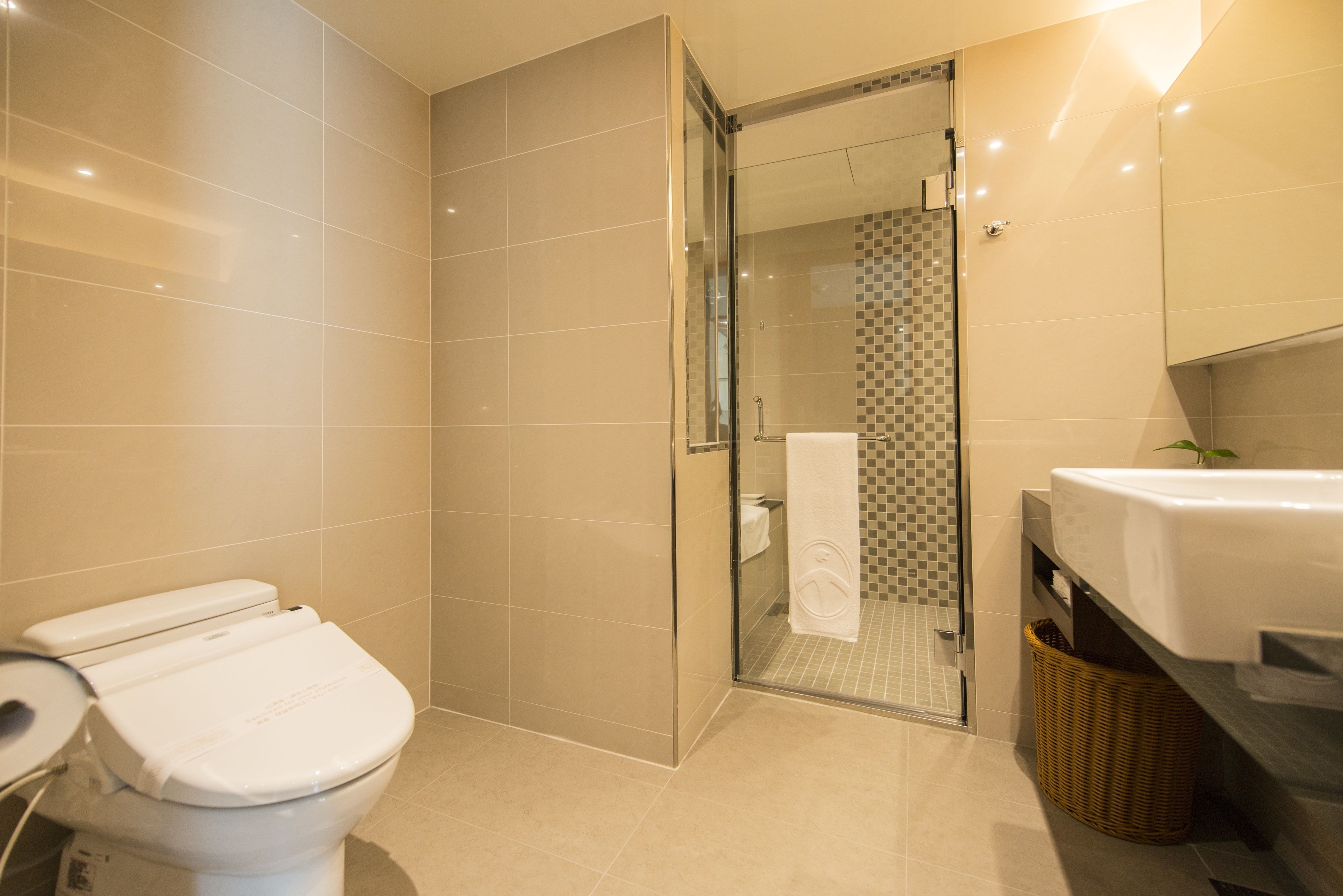 A modern bathroom with a toilet, shower, and sink.