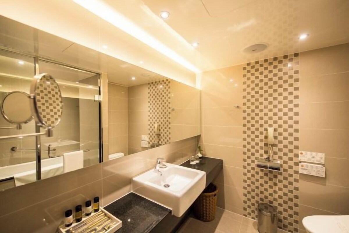 A modern bathroom with a large mirror, a sink, and a shower area.