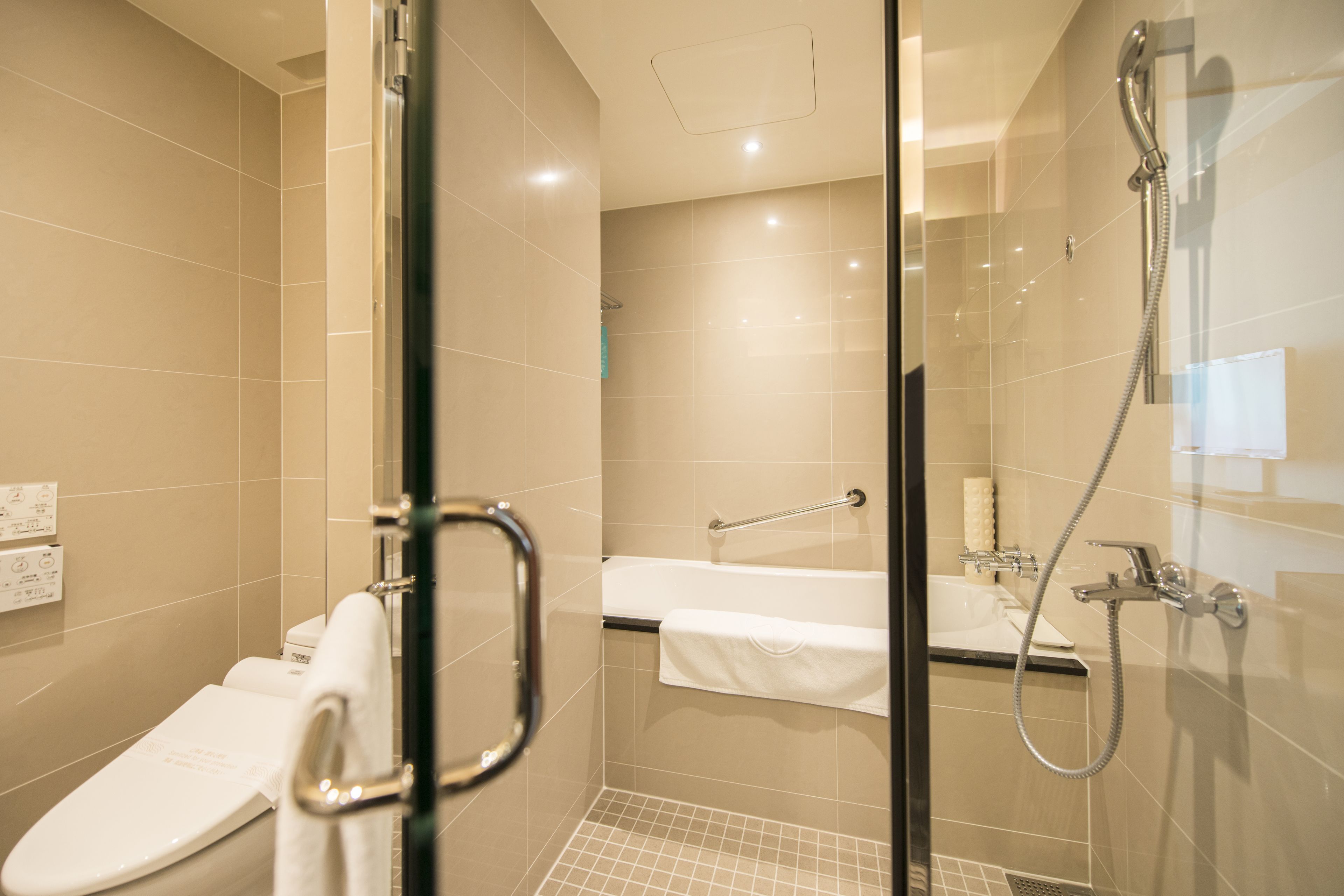 A modern bathroom with a glass-enclosed shower, a white toilet, and a sink with a towel rack.