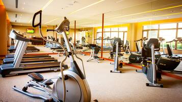 Un gimnasio con cintas de correr, elípticas y otros equipos de ejercicio.