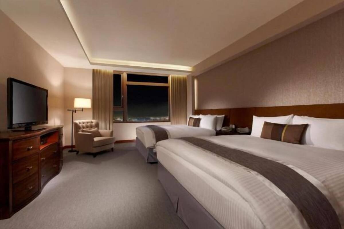 A hotel room with a large bed, a TV, a desk, and a chair.