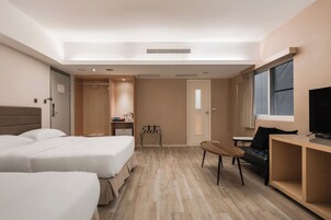 Habitación de hotel con dos camas, un escritorio, una silla, un televisor y una ventana con cortinas.