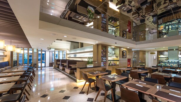 Un restaurant moderne doté de plusieurs espaces de restauration, notamment des banquettes et des tables.