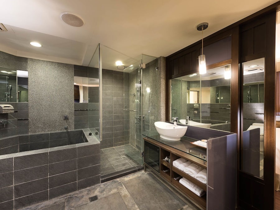 A modern bathroom with a glass-enclosed shower, a large mirror, and a vanity with a sink.