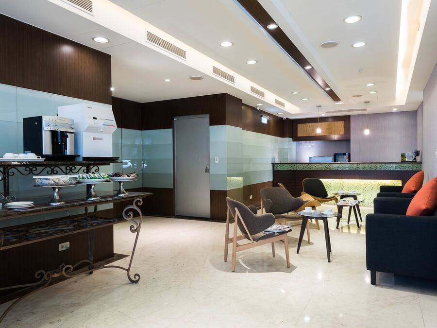 Eine moderne Hotelhalle mit Kaffeemaschine, Sitzgelegenheiten und einer Rezeption.