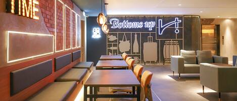 A restaurant interior with wooden tables and benches, a neon sign reading "Bottoms up!", and a brick wall with illuminated letters.