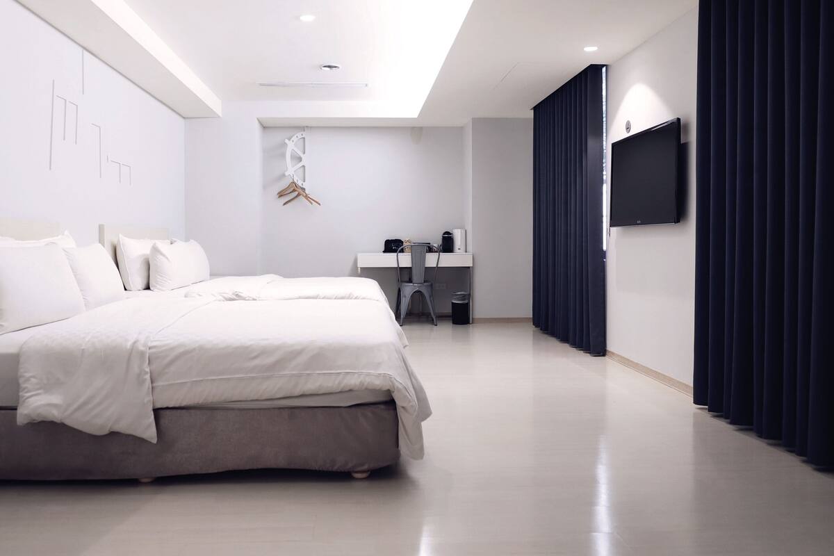 Een moderne hotelkamer met een groot bed, een bureau met een stoel, een flatscreen televisie en een donker gordijn.