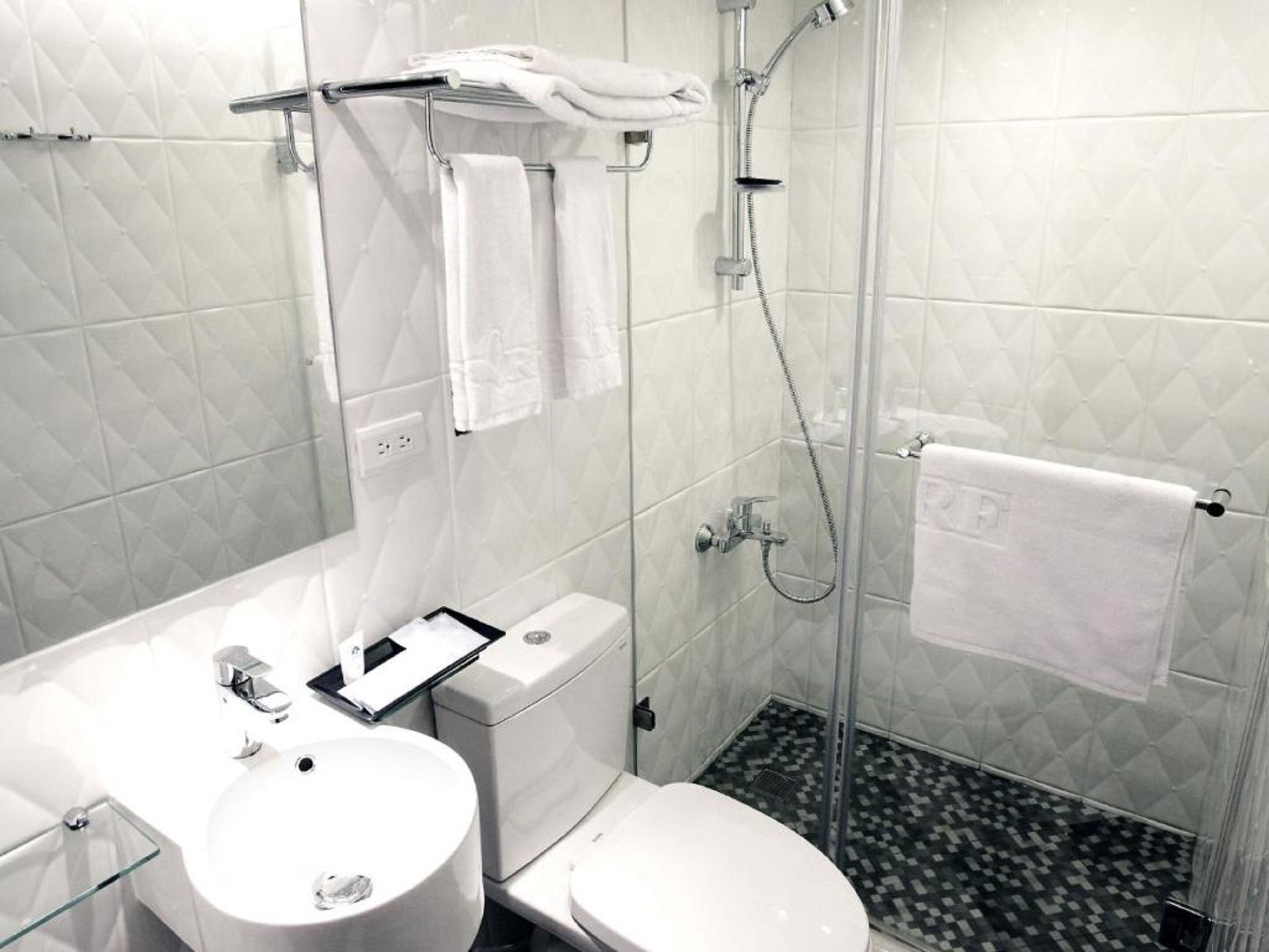 A modern bathroom with a glass shower enclosure, a white sink, and a toilet.