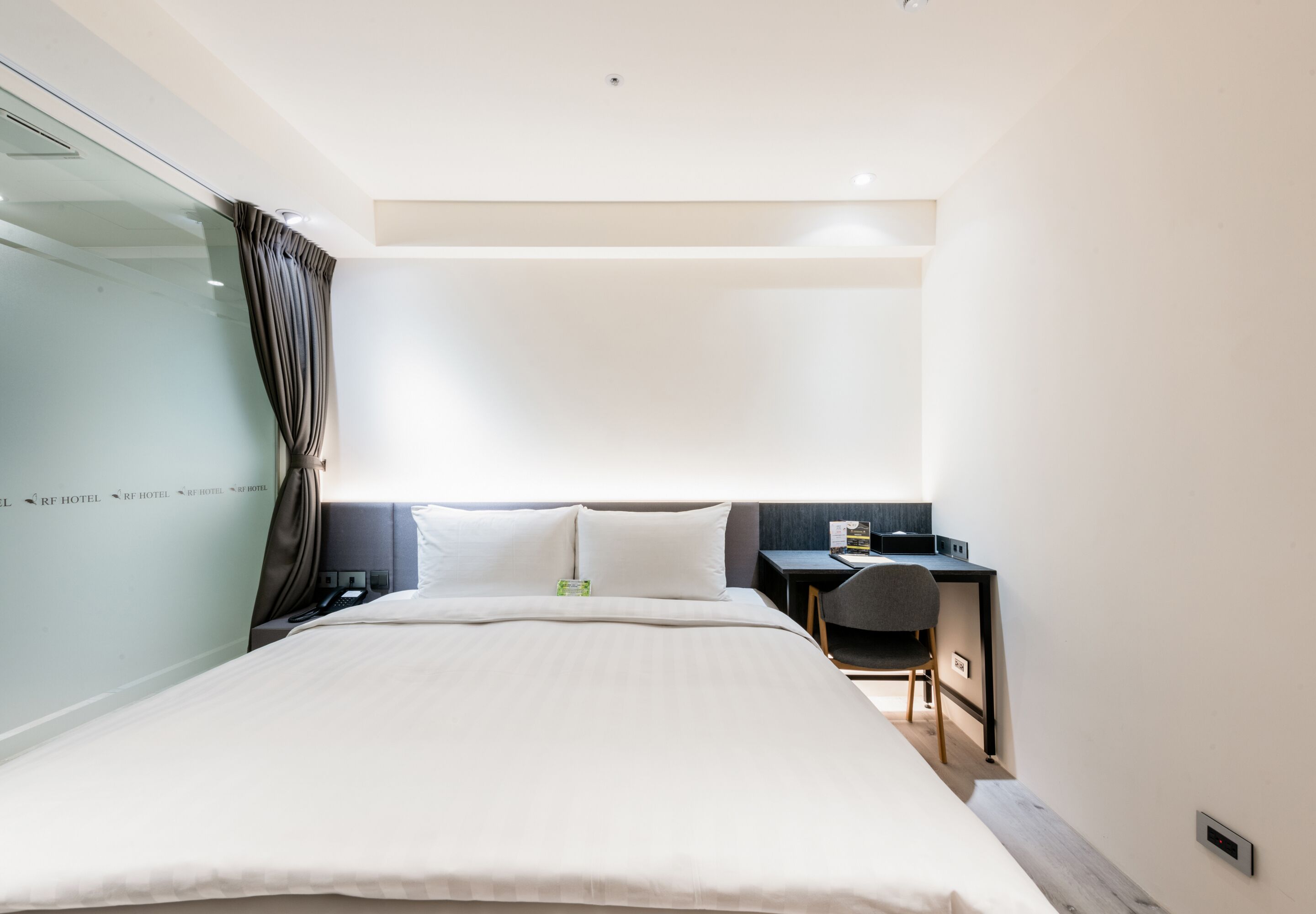 A modern hotel room with a large bed, a desk, and a chair.