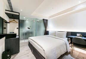 Una habitación de hotel moderna con una cama grande, un escritorio y cabina de ducha de vidrio.