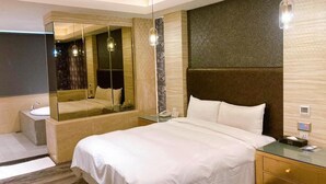 A modern hotel room with a large bed, a bedside table, a mirror, and a nightstand. - All Fun Business Hotel (Taichung)