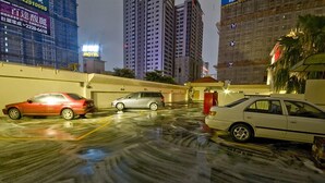 A parking lot with several cars parked, surrounded by tall buildings and a visible motel sign. - All Fun Business Hotel (Taichung)