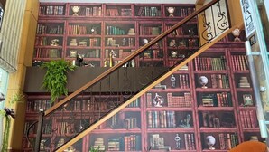 A staircase with a bookshelf background, a small table with a lamp, and an orange sofa. - All Fun Business Hotel (Taichung)