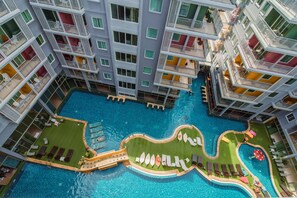 Un hotel de varios pisos con piscina central, balcones con barandillas y zonas de estar al aire libre.