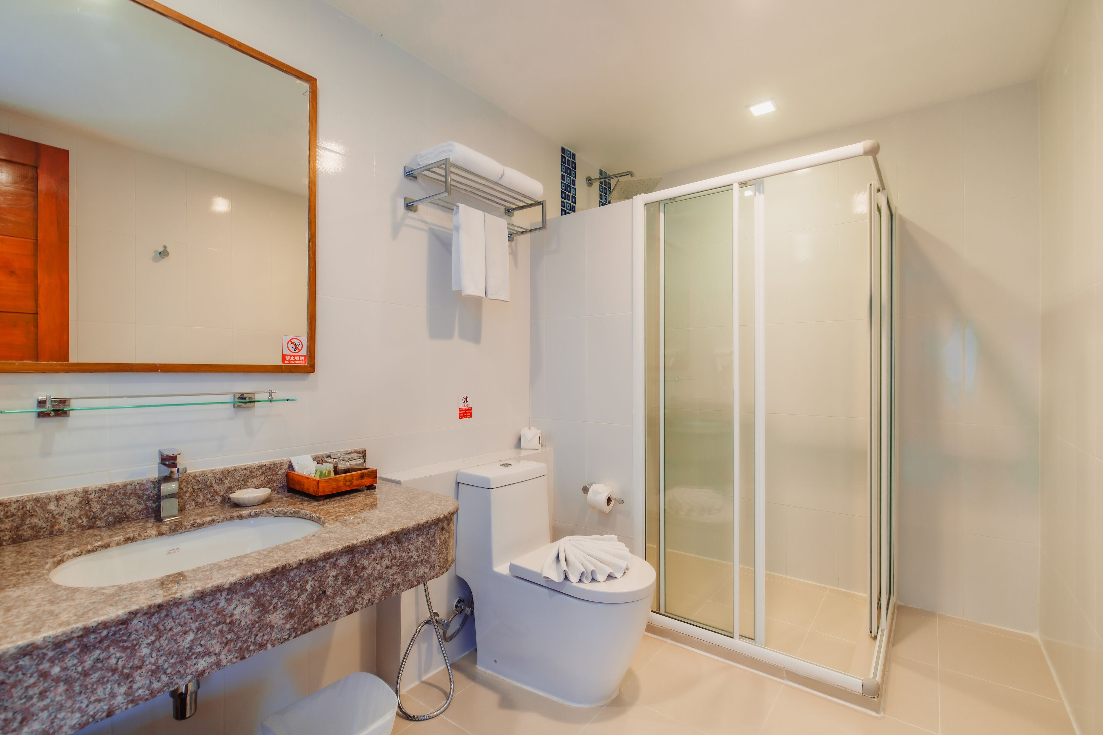 A bathroom with a granite sink, toilet, and glass shower enclosure.