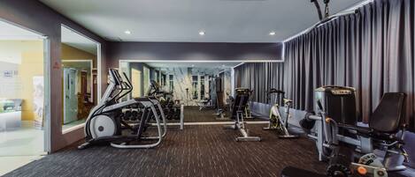 A gym with exercise equipment, a treadmill, and a mirror reflecting the space.