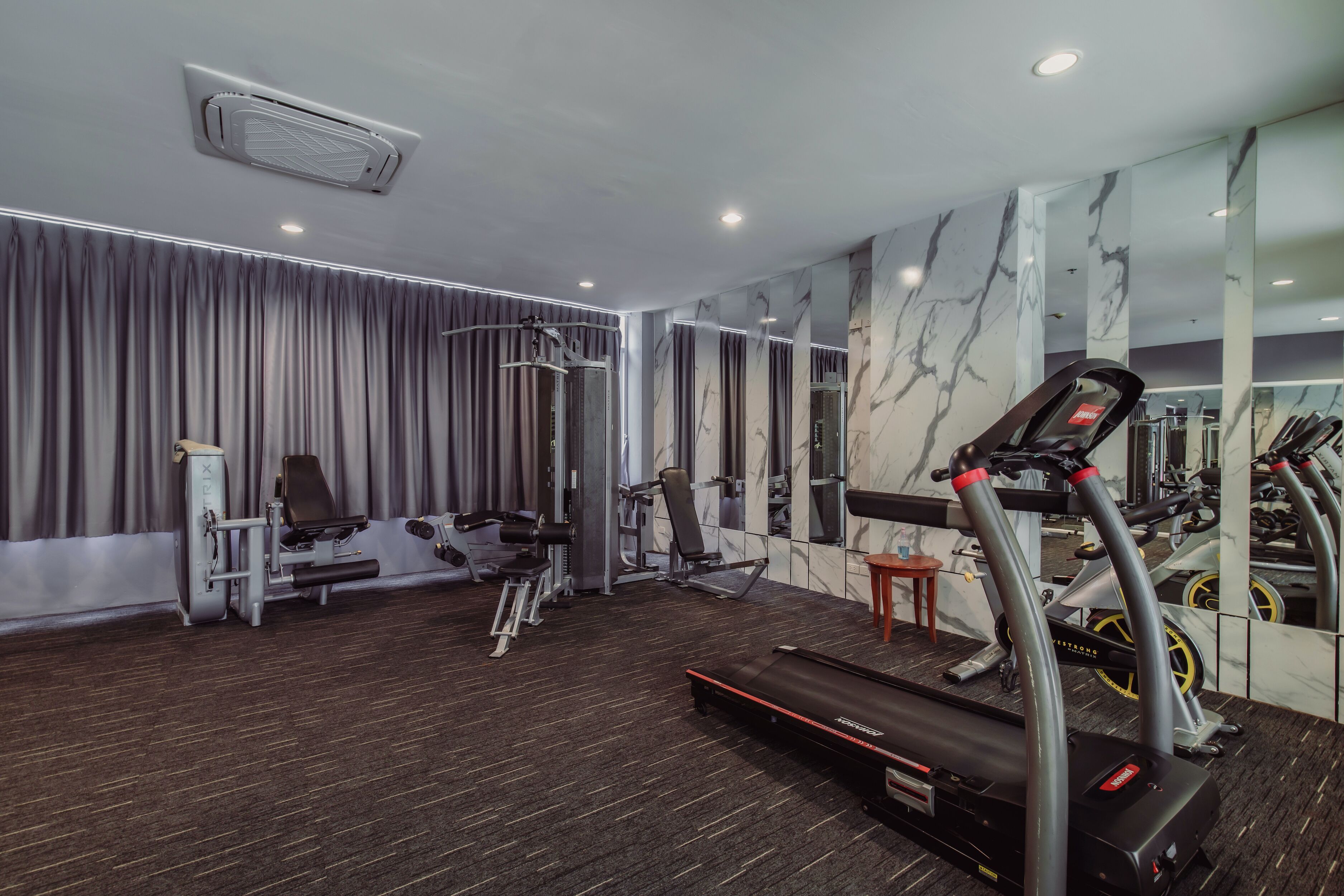Un gimnasio con cinta de correr, elíptica y máquinas de pesas.