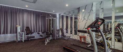 Un gimnasio con cinta de correr, elíptica y máquinas de pesas.
